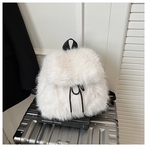 Détail d'un sac à dos blanc en fausse fourrure avec cordon noir sur une valise