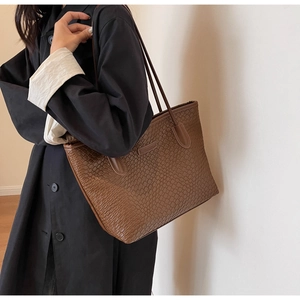 Detail of dark brown crocodile pattern tote bag showing texture and slim shoulder straps
