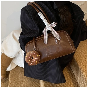 Brown vintage Boston bag detail with plush donut charm and stylish lace ribbon on the handle