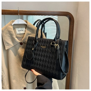 Detail of black quilted leather handbag with gold hardware and heart-shaped charm