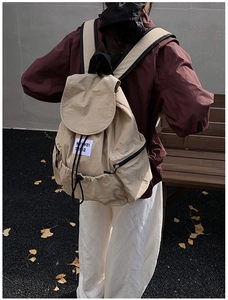 Vue extérieure d'un sac à dos beige à cordon avec logo blanc et ambiance automnale