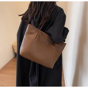 Detailed close-up showing the brown woven texture and metal logo of the large tote bag