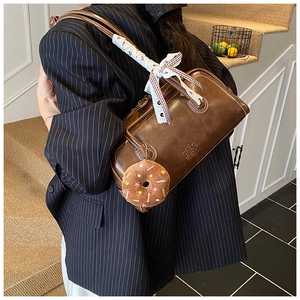 Detail of dark brown leather handbag with lace bow and plush donut charm accessory