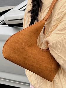 Retro caramel suede crescent underarm bag shown worn on shoulder by model in casual style