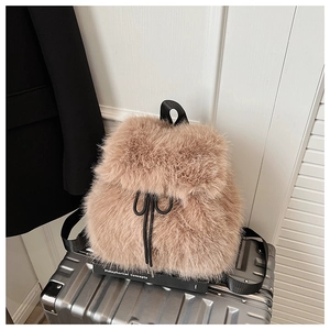 Détail d'un sac à dos en fausse fourrure camel avec nœud de serrage sur valise argent