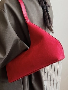Chic red crescent-shaped suede shoulder bag with metallic bottom rivets and sleek leather strap