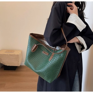 Detail of green woven tote bag with brown leather trim and Luckybag logo tag