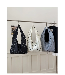 Drei minimalistische Satin-Shopper mit Punkten in Schwarz, Weiß und Blau am Kleiderbügel