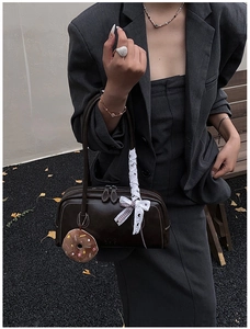 Detail of dark brown vintage Boston bag with donut charm and white lace bow accessory