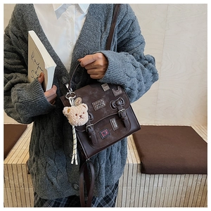 Detailed shot of dark brown PU leather crossbody bag with cute patches and plush bear charm