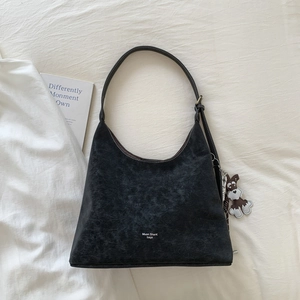 Detailed view of black retro textured underarm bag with adjustable strap and cute dog charm