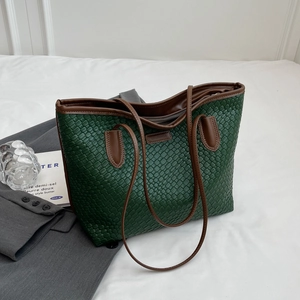 Detail shot of the vintage woven tote bag texture in dark green with brown straps