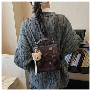 Detailed view of the dark brown leather backpack featuring vintage patches and bear pendant