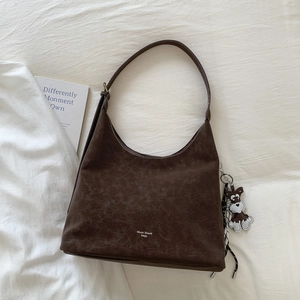 Close-up of retro brown tote bag with contrast stitching and a dog plush keychain