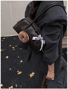 Detailed view of brown retro underarm bag with contrast stitching and donut charm