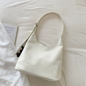Close-up of creamy white hobo bag on white fabric with a cute brown bear charm