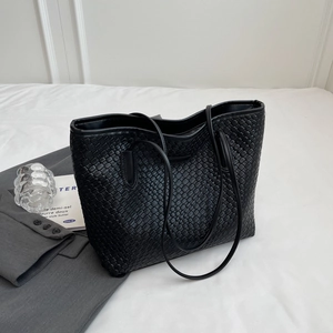 Close-up of black woven texture tote bag with premium leather finish and long straps