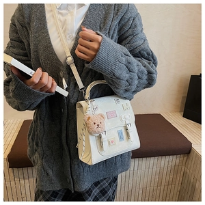 White PU leather crossbody bag with pink heart patches and brown plush bear charm detail