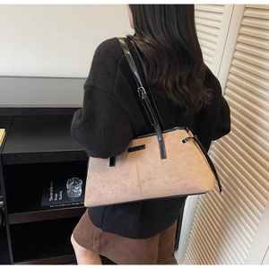 Detail showing high-capacity brown suede shoulder bag with black patent leather straps
