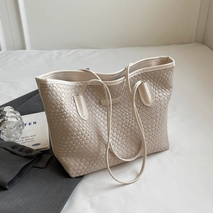 Detail of beige woven texture tote bag with slim straps in a minimalist lifestyle setting