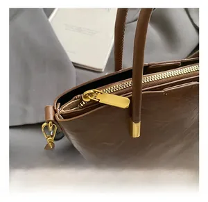 Detailed close-up of dark brown leather tote bag with high-quality gold zipper and D-ring