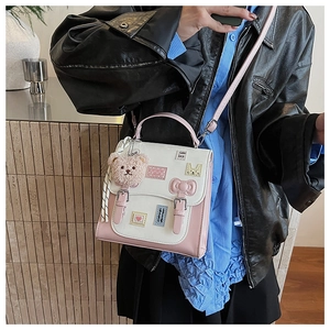 Detail of pink and white crossbody bag with plush bear charm and adjustable strap