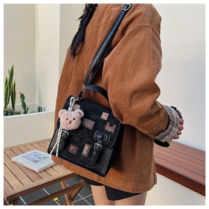 Vintage black crossbody bag with bunny patch and plush bear charm shown in lifestyle setting