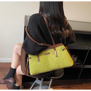 Detail of green suede shoulder bag with brown leather trim and Meigefei logo plate
