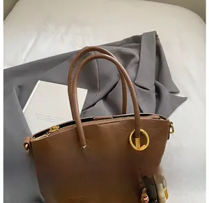 Detail view of large brown faux leather bucket bag with colorful wood bead charm