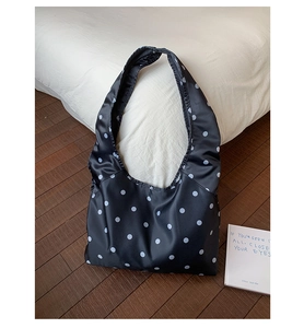Detailansicht der schwarz-weiß gepunkteten Satin-Tote-Bag auf einem gemütlichen Holzboden