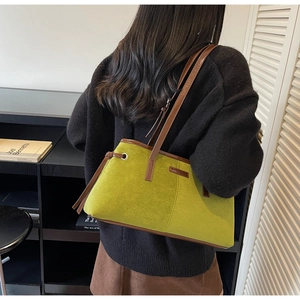 Detail view of grass green suede tote bag with brown straps worn by a model