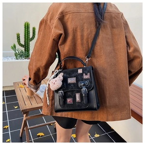Detail of black vintage school style bag with cute embroidery patches and bear charm