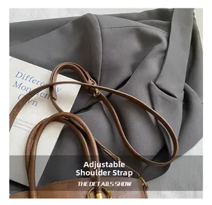 Detail of a brown tote bag featuring adjustable shoulder strap and gold-tone metal hardware
