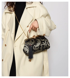 Détail du sac en satin noir avec broderie florale dorée et élégant pompon noir