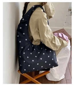 Nahaufnahme der schwarz-weißen Polka-Dot-Satintasche mit glatter Textur und weichem Fall