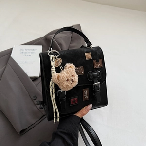 Detail of black crossbody bag featuring cute plush bear and Good Luck embroidery