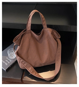 Détail d'un sac cabas en tissu à carreaux marron sur un support en bois avec des livres