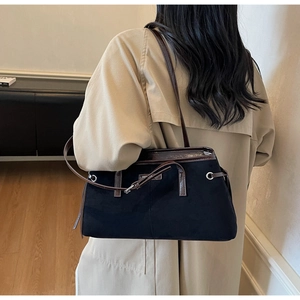 Detail of vintage black suede tote bag with contrast leather trim on trench coat outfit