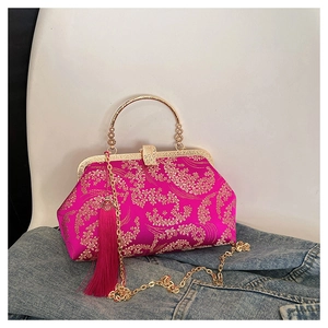 Detail of rose red embroidery shell bag with golden floral patterns and long silk tassel
