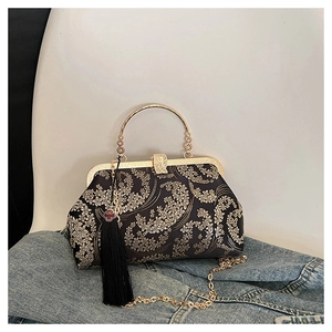 Close-up of vintage shell bag with gold floral embroidery and decorative black tassel