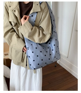 Detailansicht der großen gepunkteten Satin-Tote-Bag an der Schulter eines Models