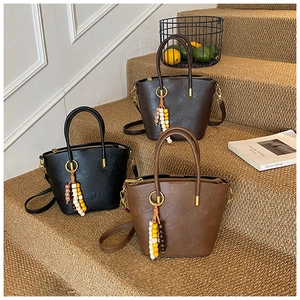 Detailed view of retro bucket bags in black and brown leather with beaded charms