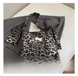 Detail shot of leopard print canvas tote bag with matching small pouch on a grey blazer