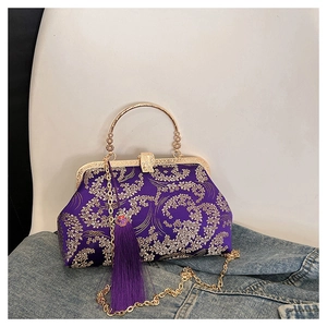 Close-up of purple shell bag with golden embroidery, metal handle and tassel detail