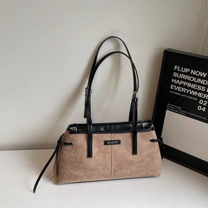 Detail of khaki suede tote bag showing black leather stitching and brand label logo