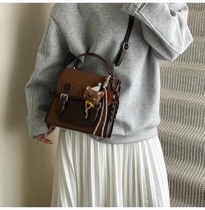 Detail of vintage color-block crossbody bag with buckle decor and bear charm