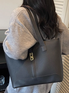 Sac fourre-tout en cuir noir à motif litchi avec fermoir doré porté par un mannequin
