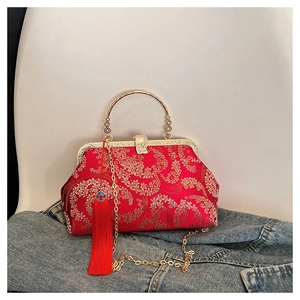 Detailed shot of red Chinese silk embroidery handbag with gold floral patterns and tassel