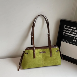 Detail of green velvet shoulder bag with brown leather trim and metallic brand plaque