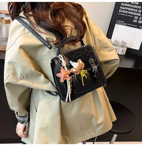 Detail of vintage black backpack featuring leopard print flap and cute bear pendant